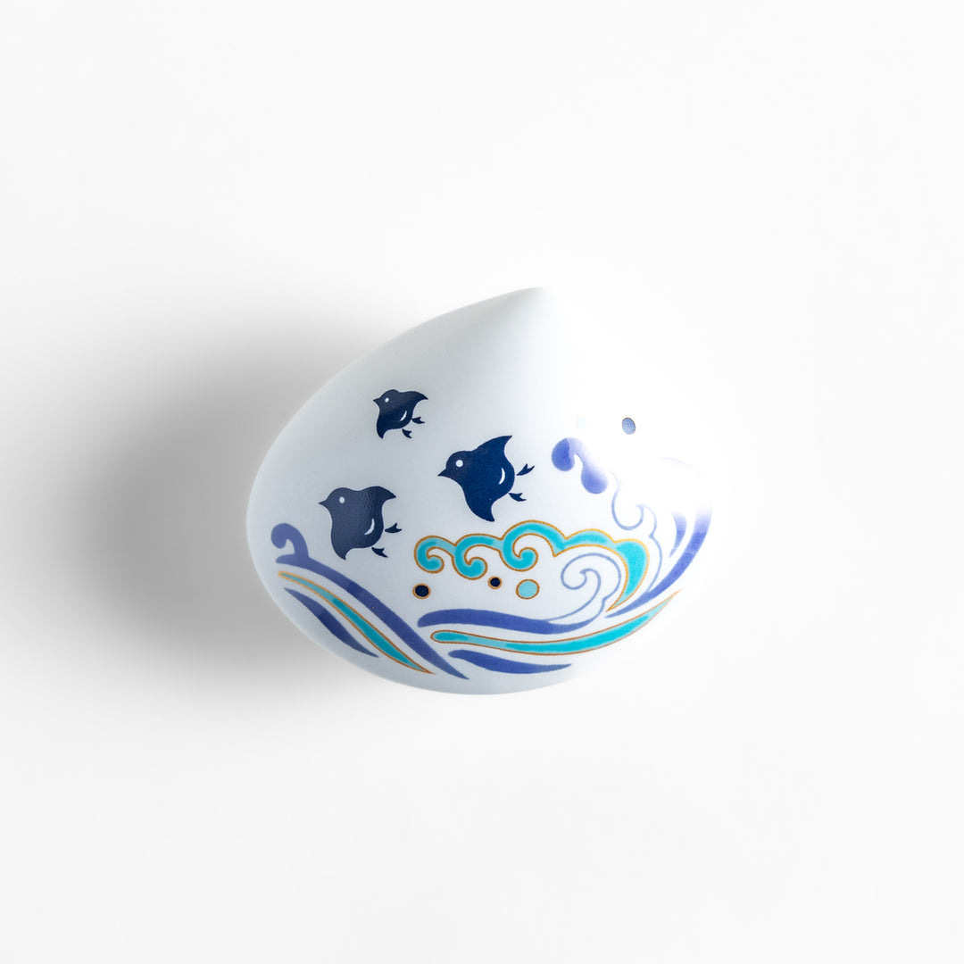 White ceramic incense holder shaped like a seashell, featuring an elegant blue wave and seabird motif, with a small rounded holder inside for secure incense placement.