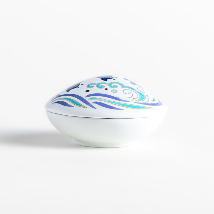 White ceramic incense holder shaped like a seashell, featuring an elegant blue wave and seabird motif, with a small rounded holder inside for secure incense placement.