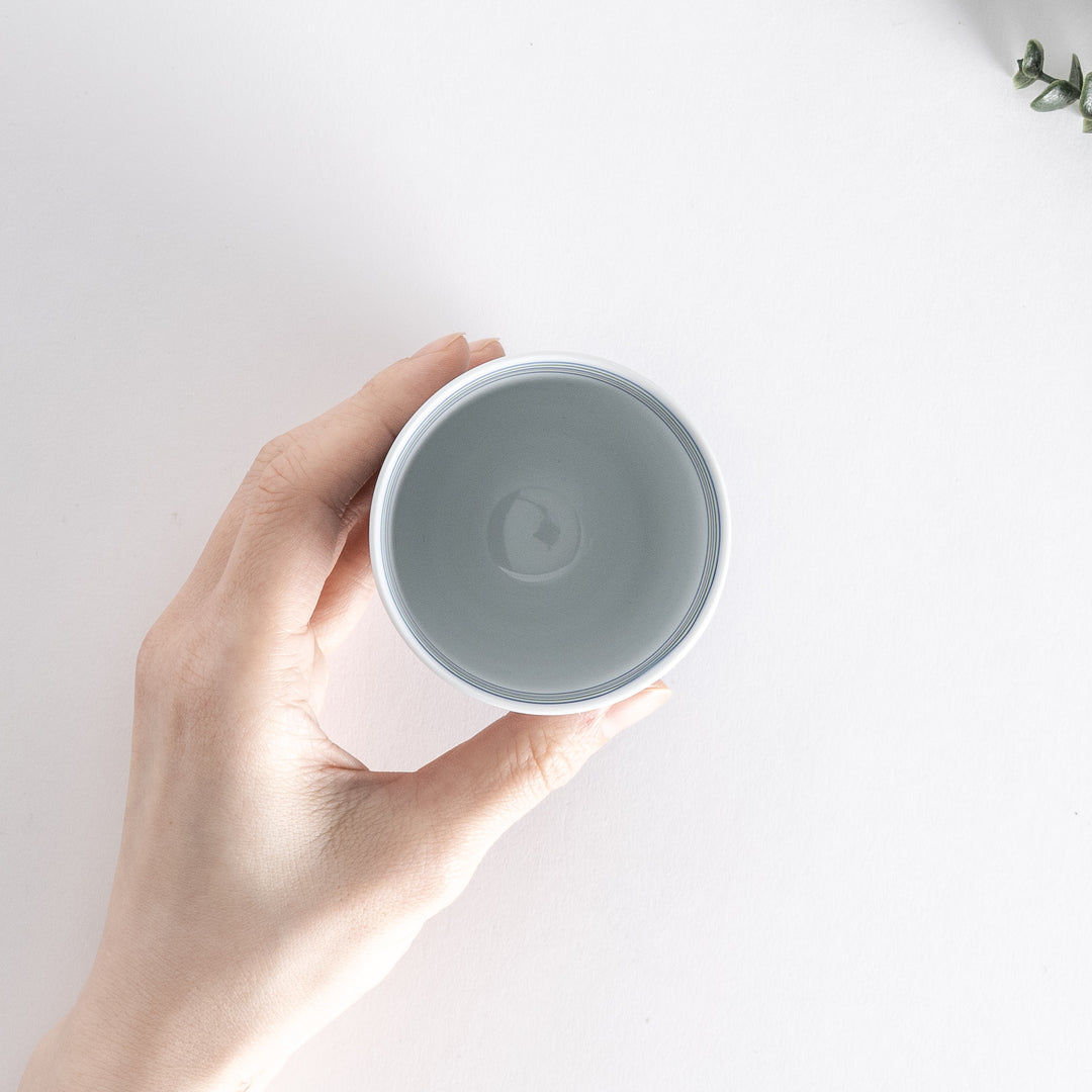 Hand holding a Serene Strip Tea Cup, showing the circular opening and striped pattern interior.