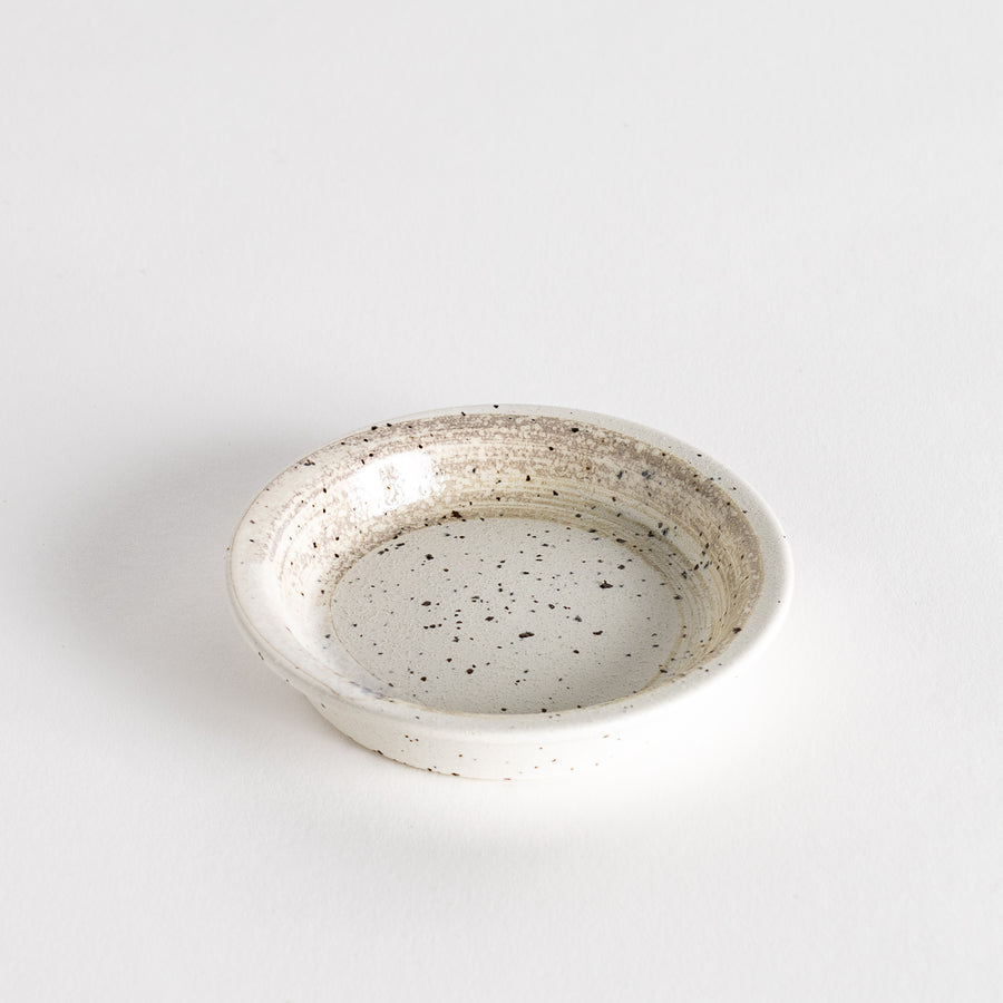 A shallow, off-white dish with a speckled glaze and a slightly textured finish.