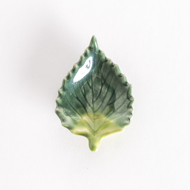 A ceramic shiso leaf chopsticks rest in shades of green with delicate veins and textured edges.