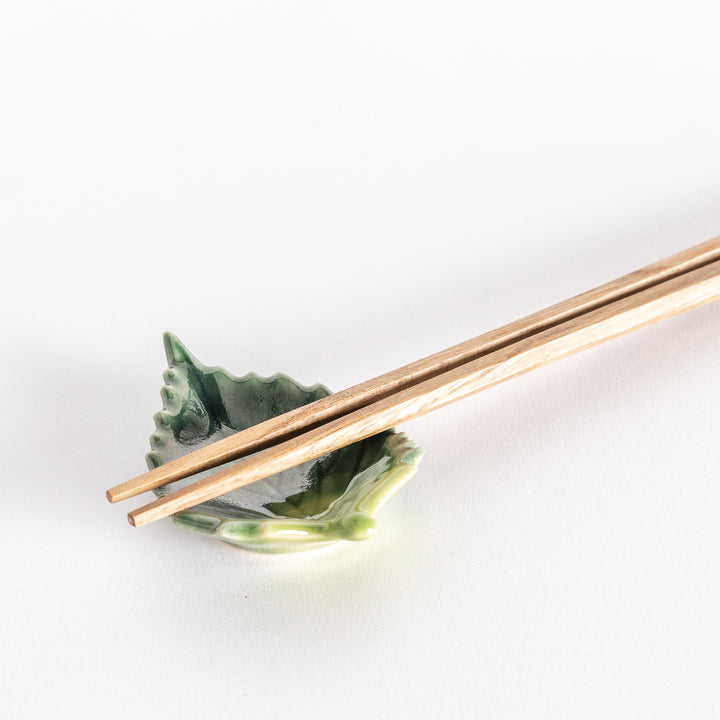 Close-up of the shiso leaf chopsticks rest with chopsticks resting neatly on its textured surface.