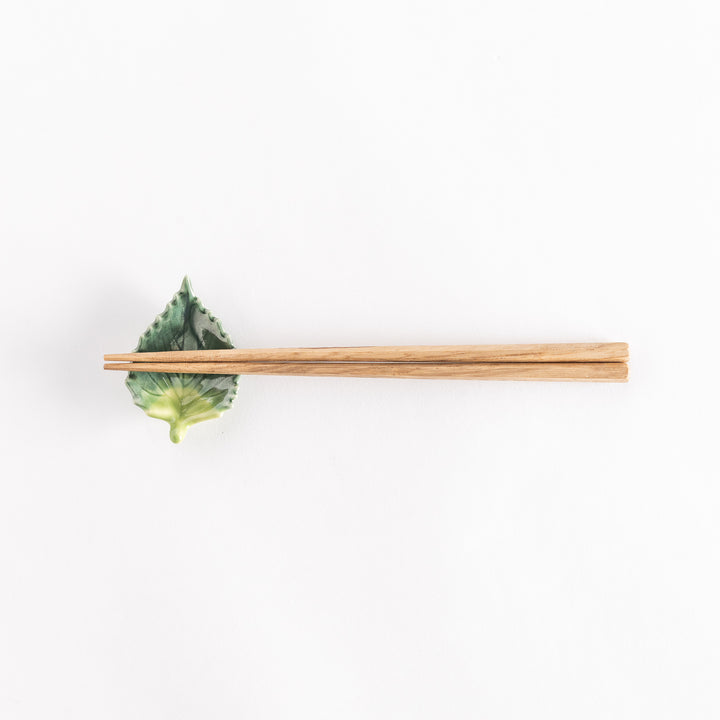 Full view of the shiso leaf chopsticks rest with chopsticks placed across its central ridge.