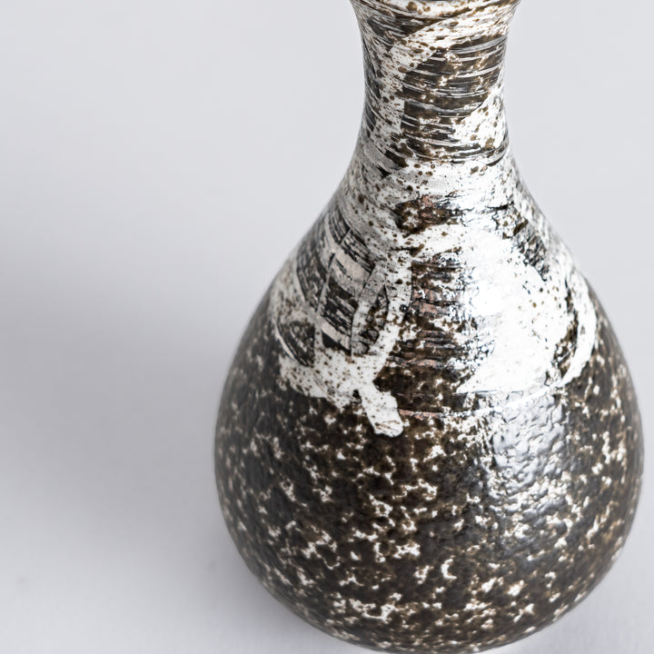 Close-up of the sake flask, showcasing the detailed texture and silver highlights on the surface.