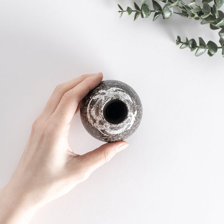 Top-down view of the sake flask held by hand, showing the textured black and silver design.