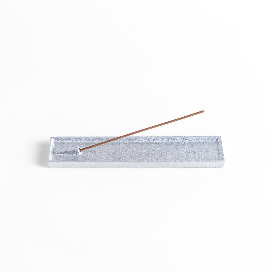 Sleek aluminum incense holder with a modern minimalist design, featuring a rectangular tray and a built-in slot to securely hold incense sticks while catching ash.