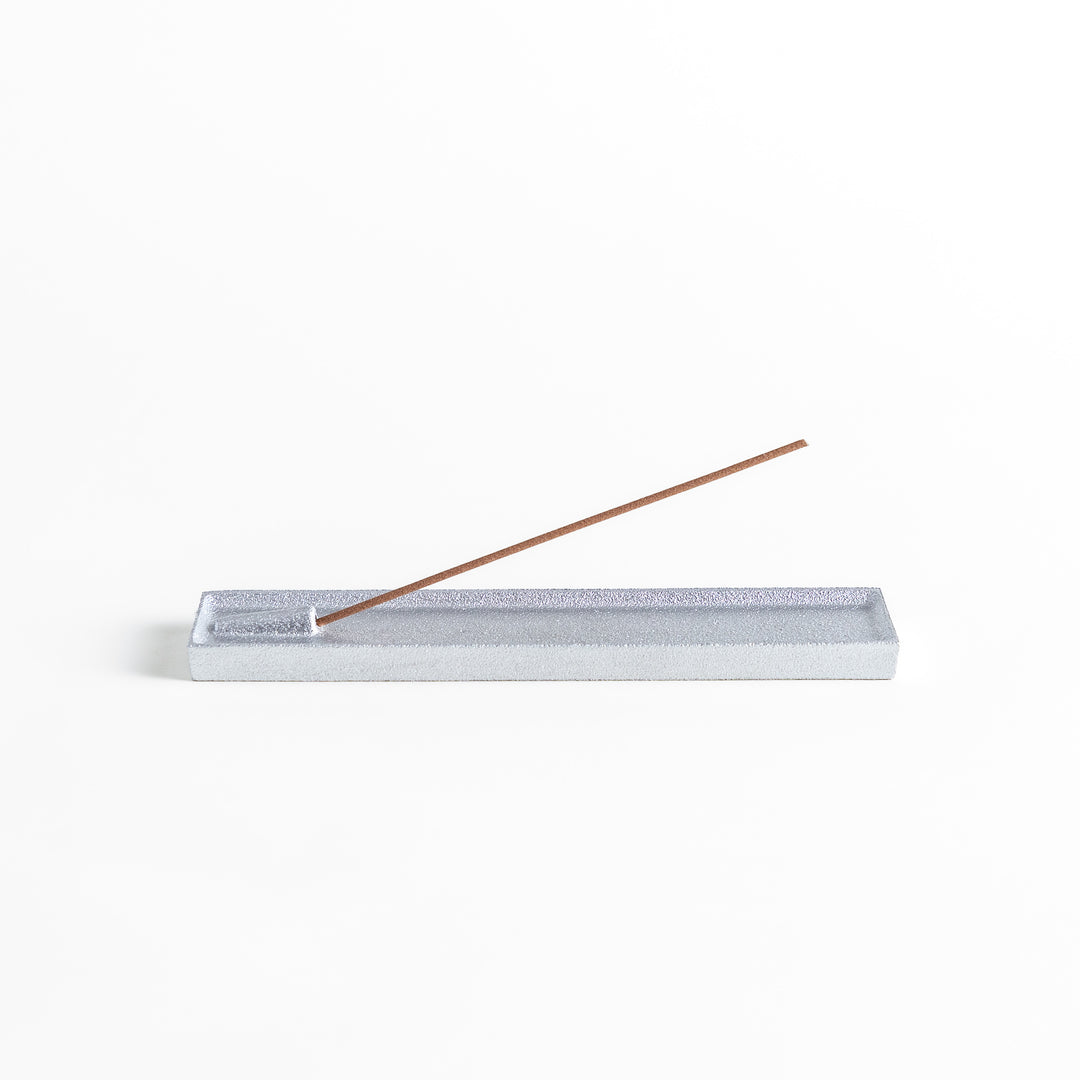 Sleek aluminum incense holder with a modern minimalist design, featuring a rectangular tray and a built-in slot to securely hold incense sticks while catching ash.