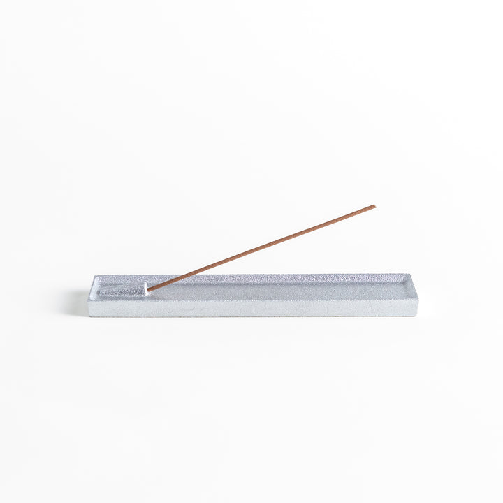 Sleek aluminum incense holder with a modern minimalist design, featuring a rectangular tray and a built-in slot to securely hold incense sticks while catching ash.