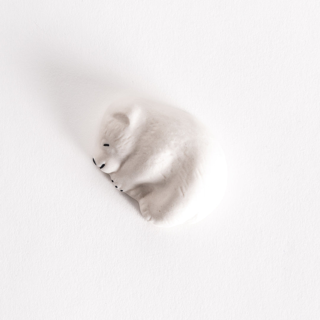 A polar bear-shaped chopstick rest, curled up and resting, on a clean white background.