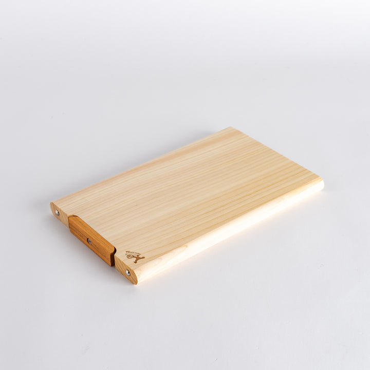 Close-up of the small hinoki cutting board, focusing on the wood texture and the design detail of the handle.