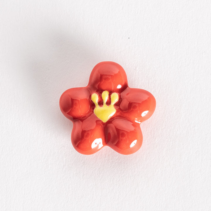 Red plum-shaped chopsticks rest with a glossy finish and a yellow center detail.