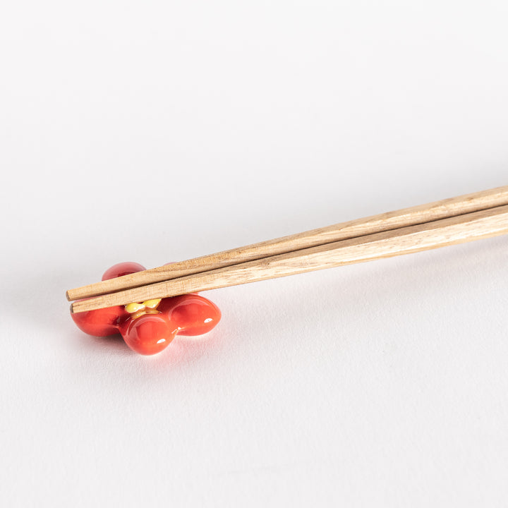 Close-up of a red plum chopsticks rest holding wooden chopsticks.