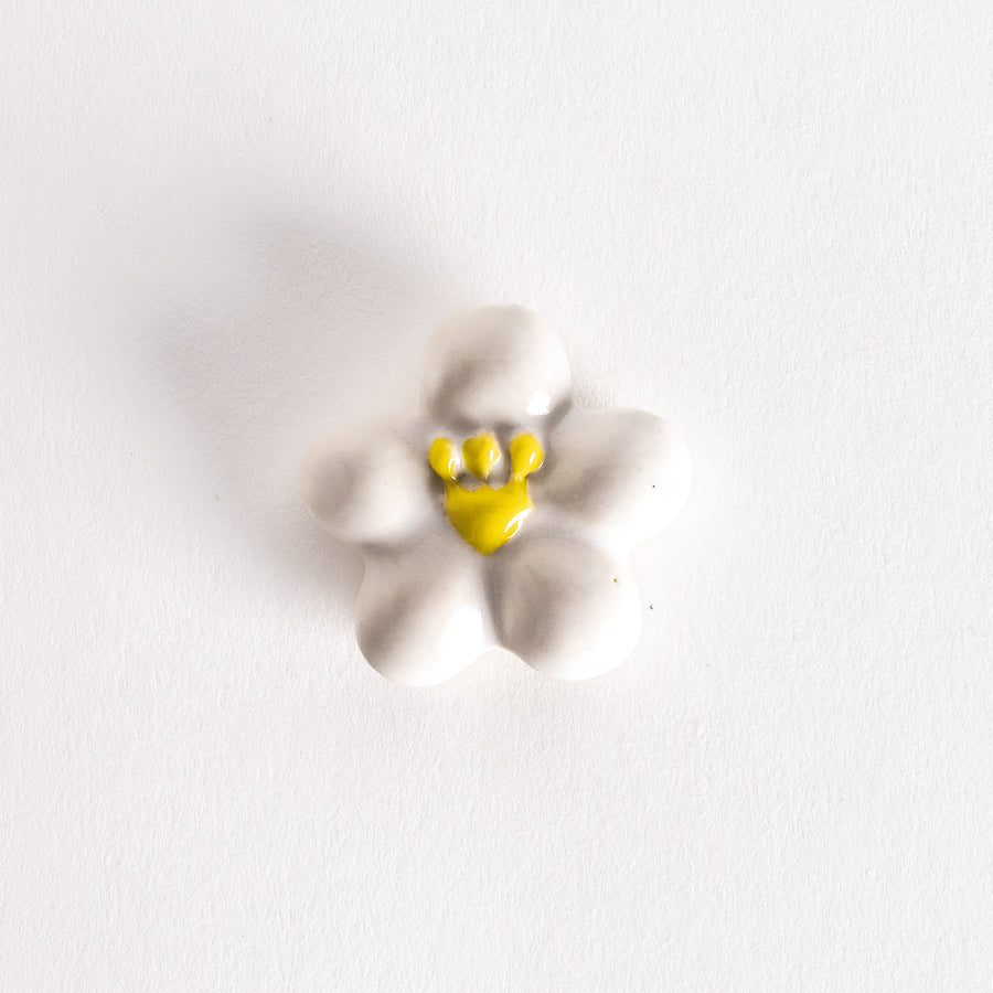 White plum-shaped chopsticks rest with a glossy finish and a yellow center detail.