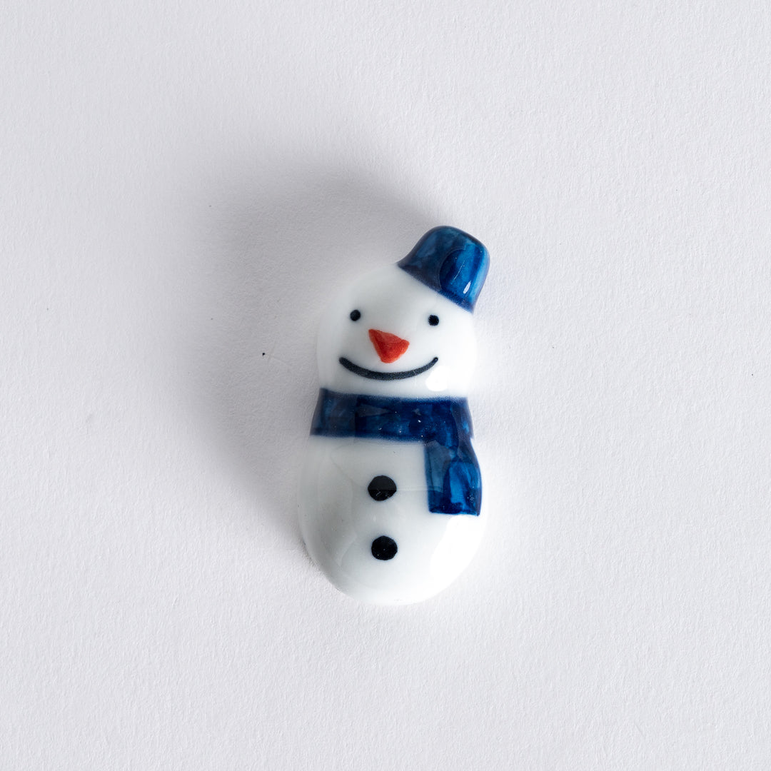 Snowman chopstick rest featuring a blue hat and scarf, designed to hold chopsticks in a charming, playful manner.