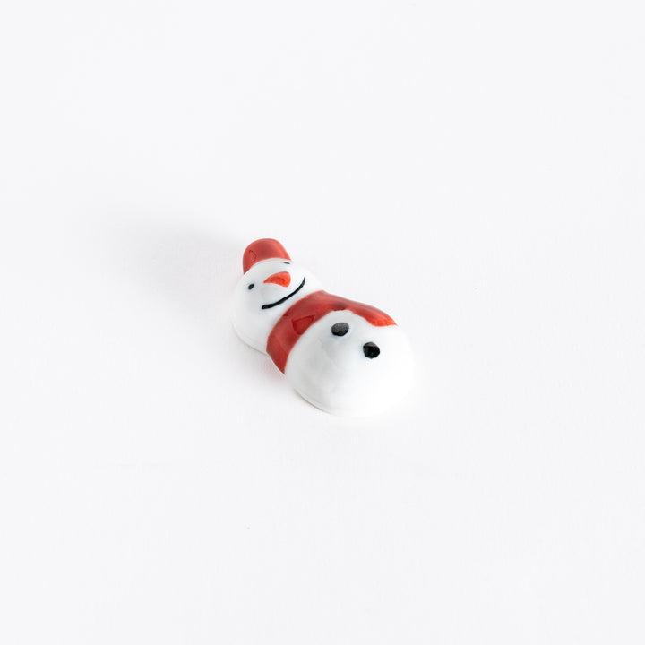 A slightly angled view of the red-scarfed snowman chopstick rest, emphasizing its round shape and charming expression.