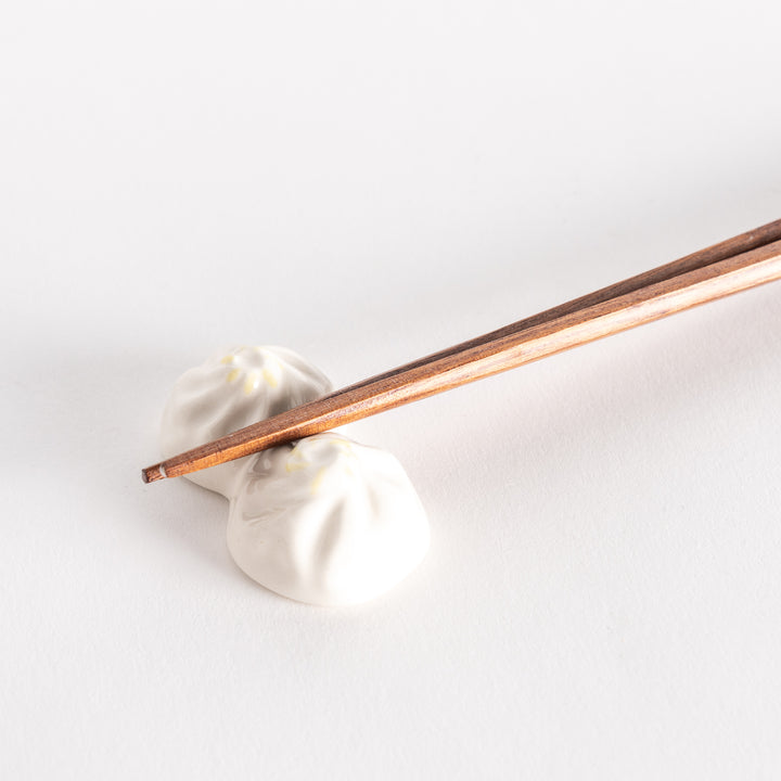 Close-up of a soup dumpling-shaped chopstick rest holding wooden chopsticks, showcasing its detailed design.