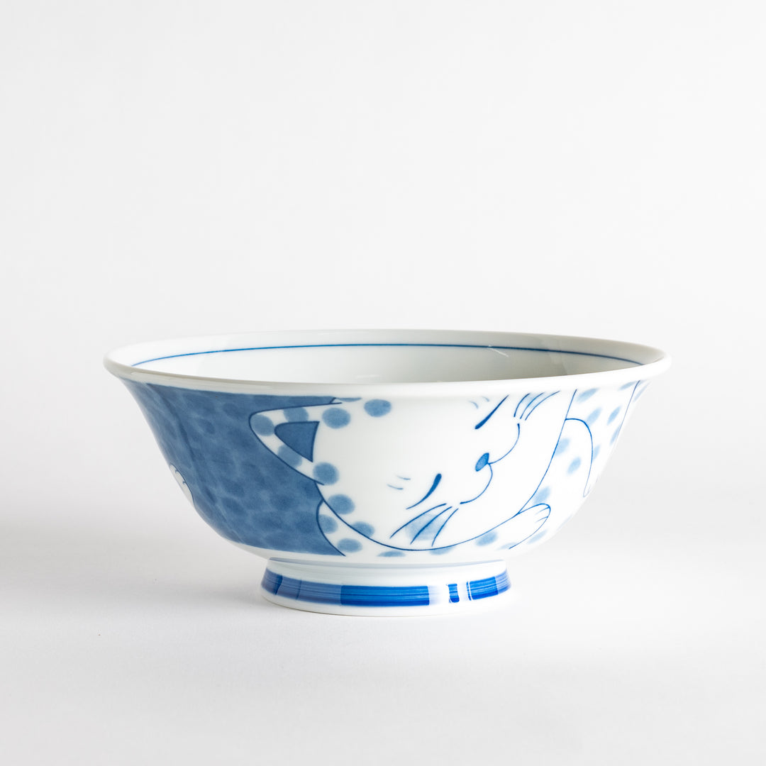 A ramen bowl with a design of a blue and white spotted cat, appearing cozy and content.