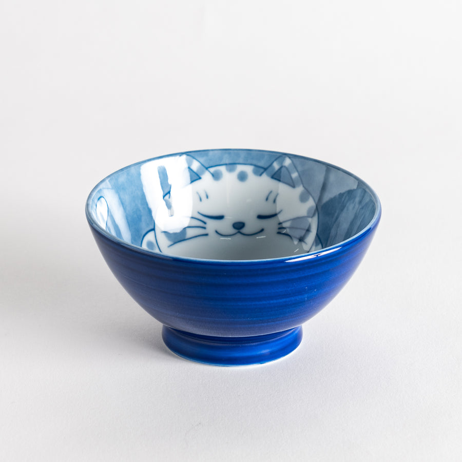 A rice bowl featuring a chubby blue-spotted white cat, sitting contentedly.