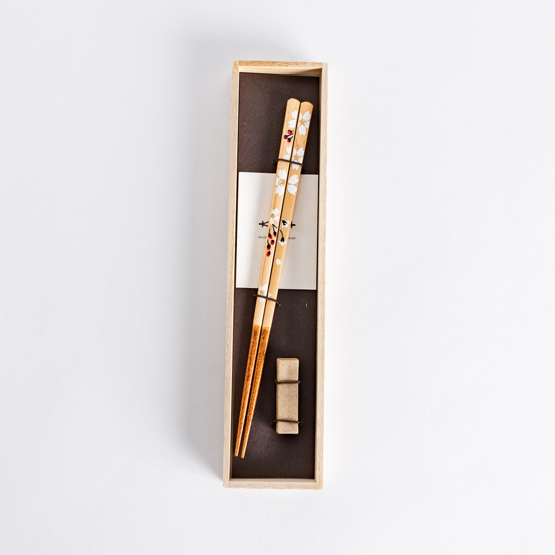 Elegant floral design on chopsticks featuring soft white flowers, placed in a light wood box with a traditional touch.