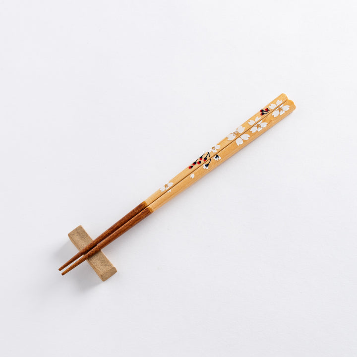 Cherry blossom-patterned chopsticks with delicate white and red floral details, featuring a refined brown tip.