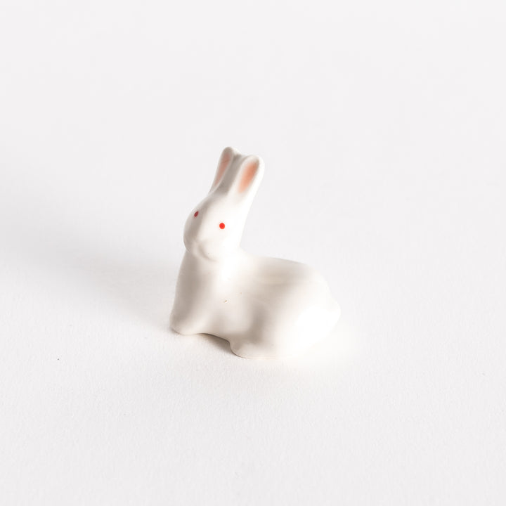 A ceramic chopstick rest shaped like a white rabbit with red eyes and soft pink ears.