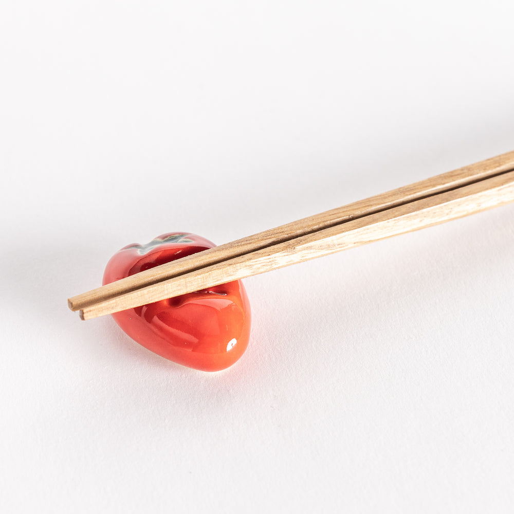 Close-up of the strawberry chopsticks rest with chopsticks placed on it, highlighting its detailed leaves and dotted seeds.