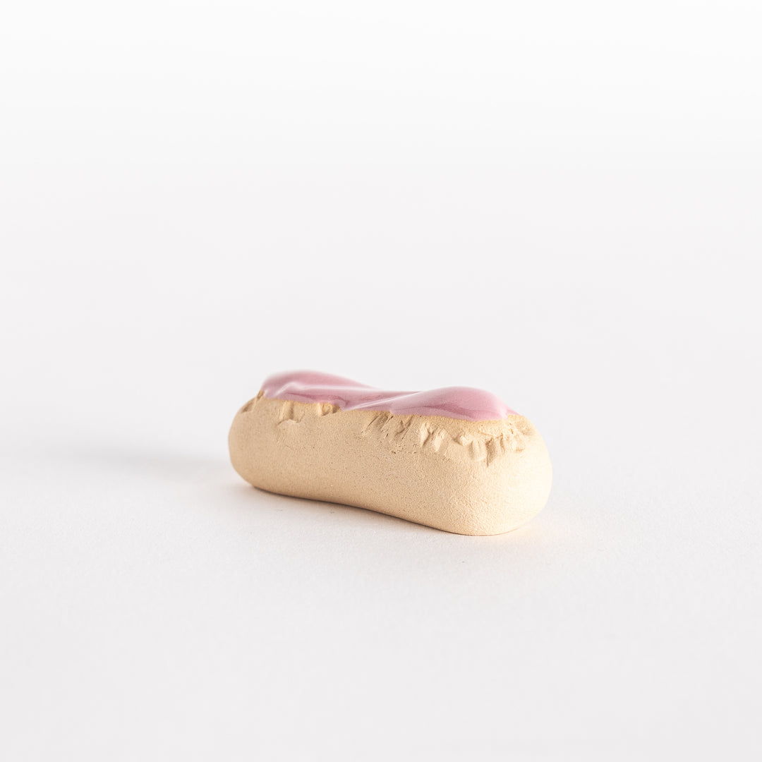 Side view of the strawberry éclair chopsticks rest, highlighting its rounded shape and biscuit-like edges.