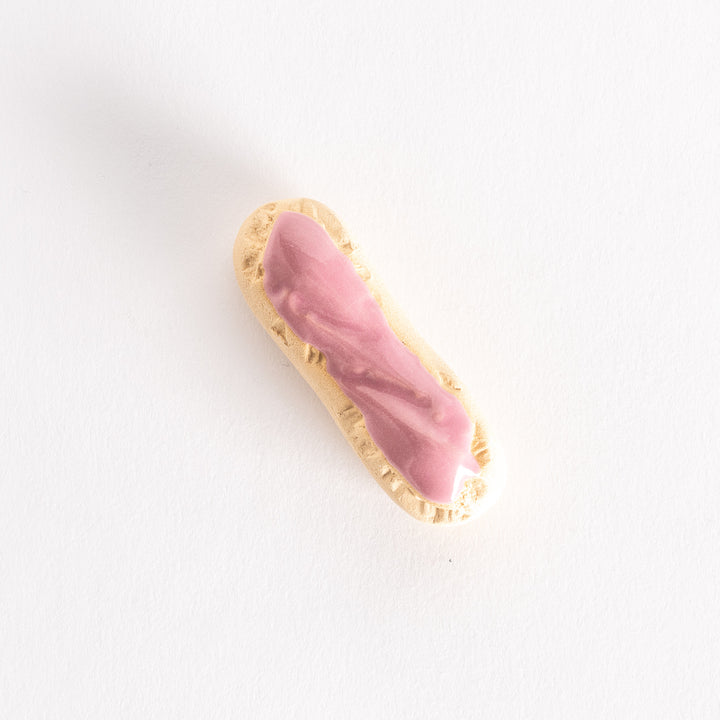 Top view of the strawberry éclair chopsticks rest, showcasing the smooth pink glaze and elongated design.