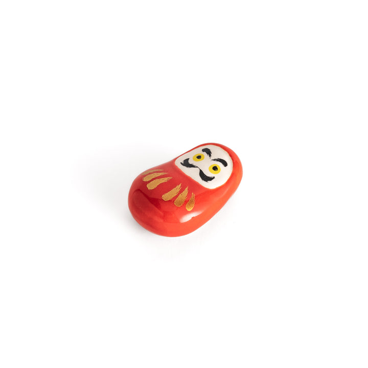 A slightly angled view of the daruma chopstick rest, emphasizing its three-dimensional shape and gold accents.