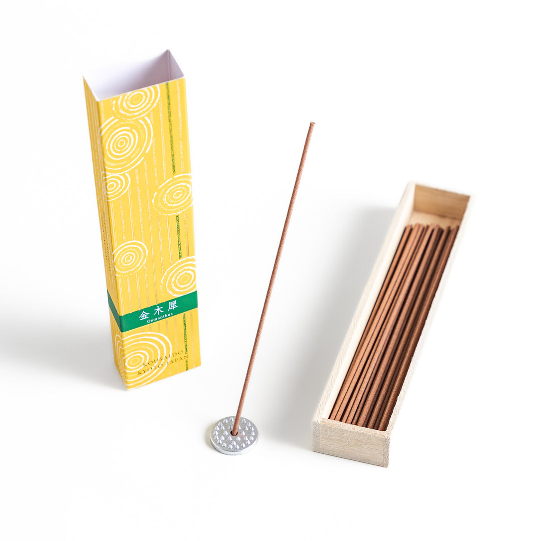 Incense in a light wooden box with warm brown sticks, elegantly packaged in a vibrant yellow design featuring white circular patterns for a refreshing and uplifting ambiance.