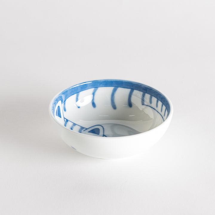 A dessert bowl with a blue-striped cat, smiling contentedly.