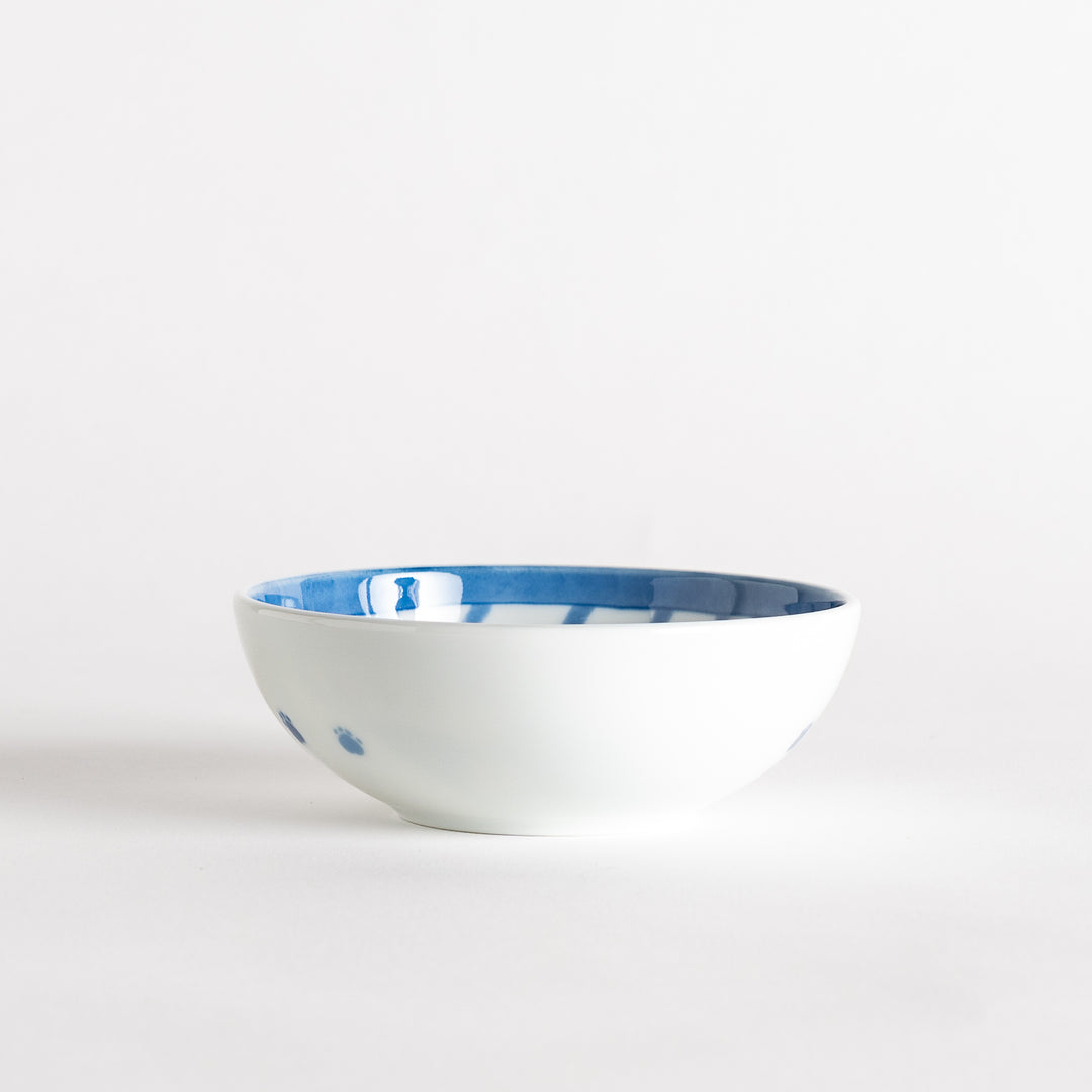 A dessert bowl with a blue-striped cat, smiling contentedly.