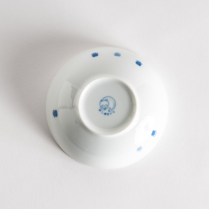 A dessert bowl with a blue-striped cat, smiling contentedly.