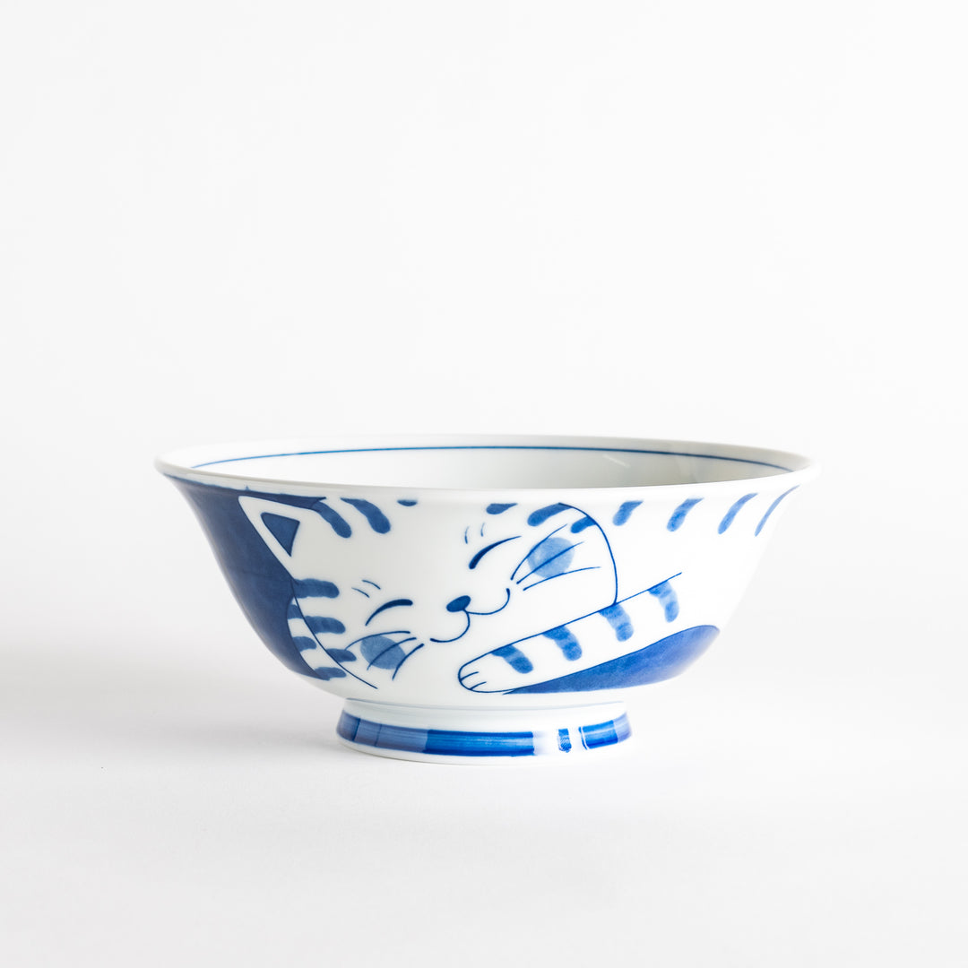 A ramen bowl showcasing a blue and white striped cat stretching out comfortably.