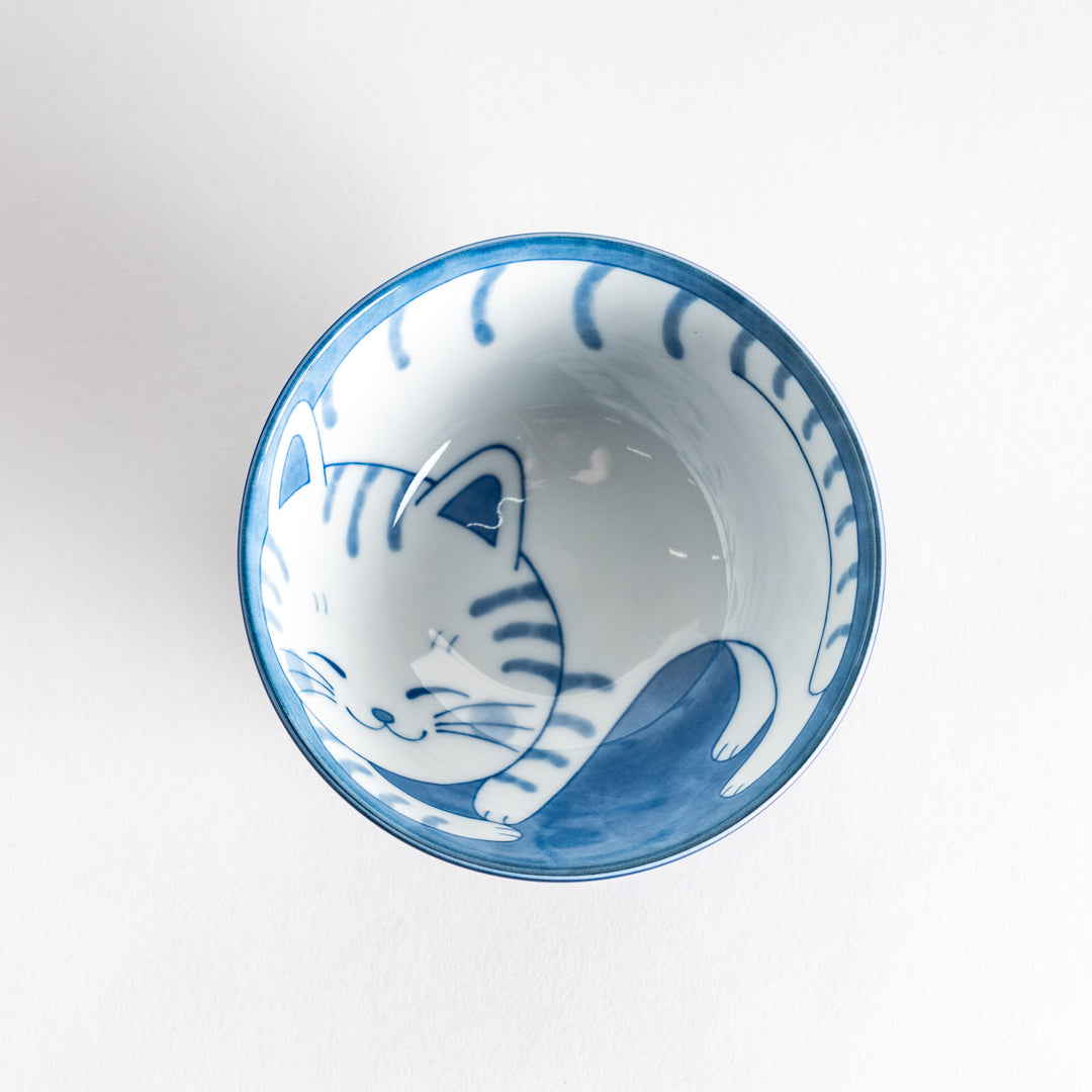 A rice bowl with a blue-striped white cat, curled up and smiling.