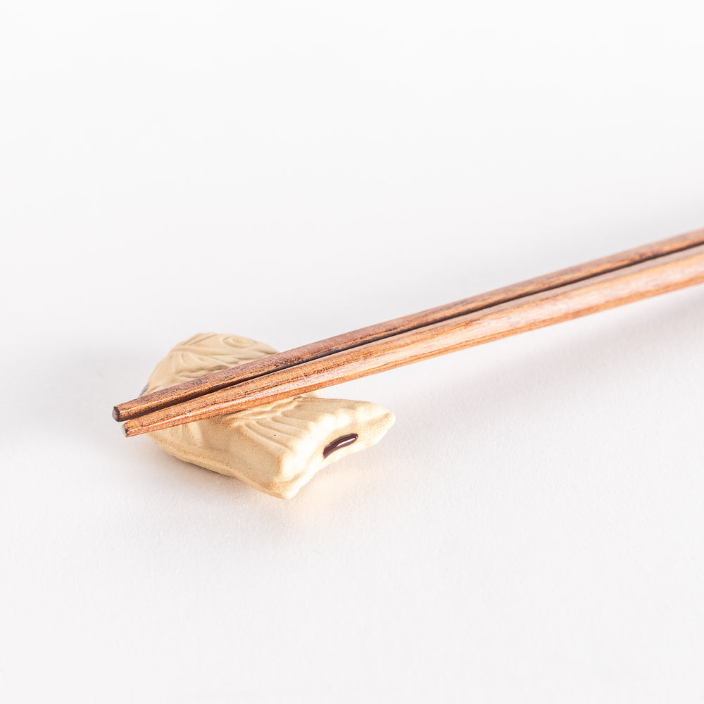 Close-up view of the taiyaki chopsticks rest with chopsticks resting on top, showcasing its textured fish design.