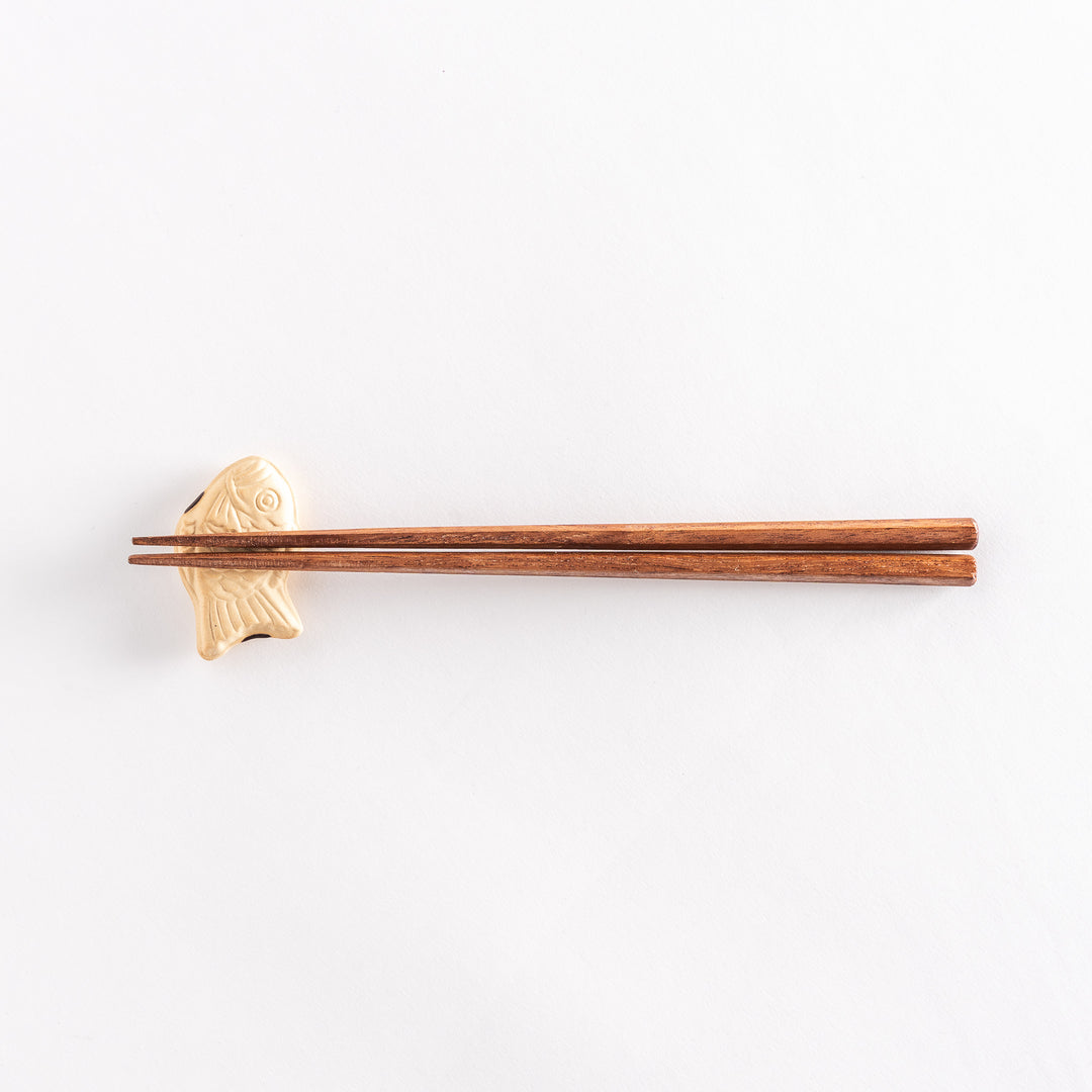 The taiyaki chopsticks rest with chopsticks placed across it, highlighting its fish-shaped form.