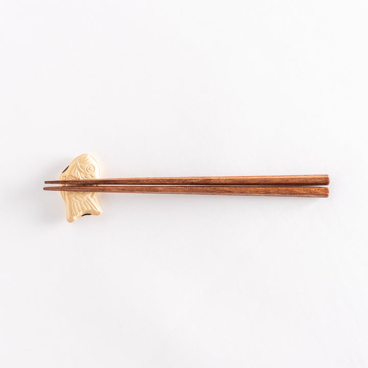 The taiyaki chopsticks rest with chopsticks placed across it, highlighting its fish-shaped form.