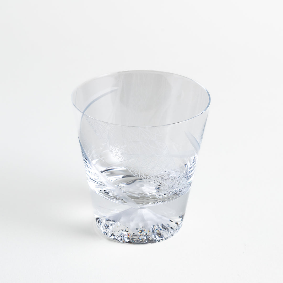 Clear glass with geometric etchings and Mount Fuji base, standing empty on a clean, white surface.