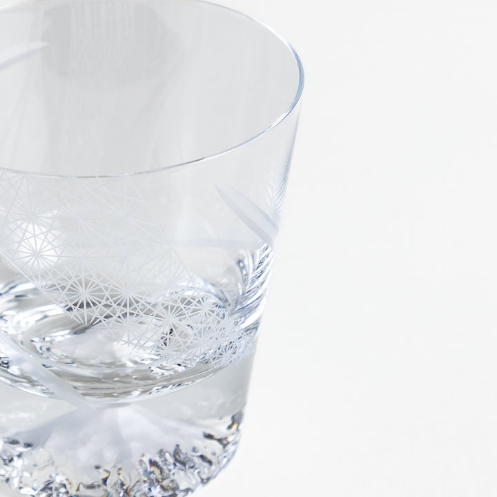 A glass with a geometric etched design and a Mount Fuji base.