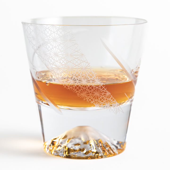 Clear glass with whisky poured inside, showcasing etched geometric patterns and the striking Mount Fuji base in golden hues.