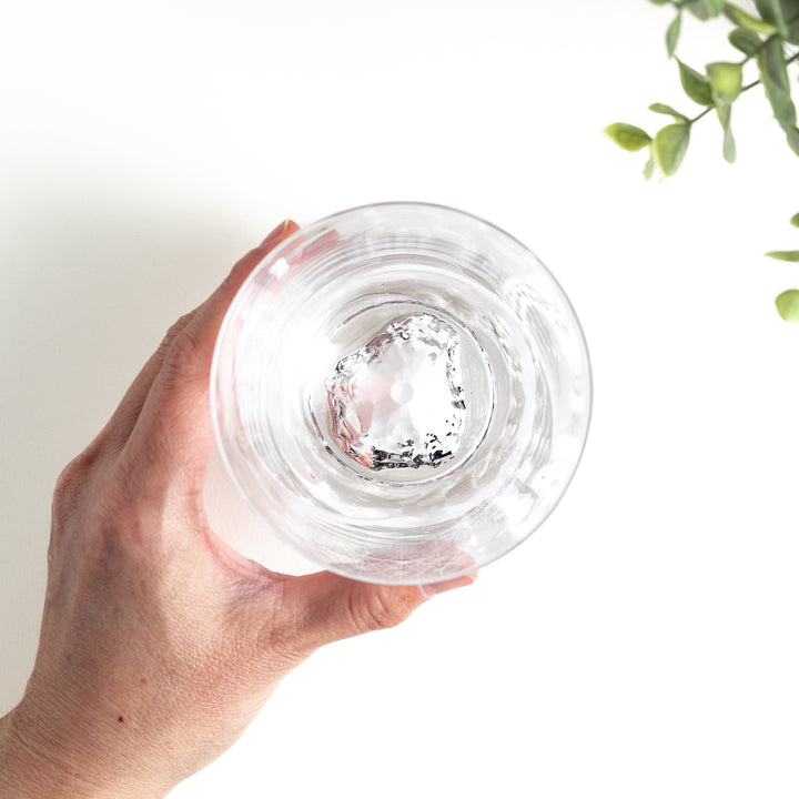 Top view of the glass showing the detailed Mount Fuji base inside. Held by hand, the glass rests against a white background.