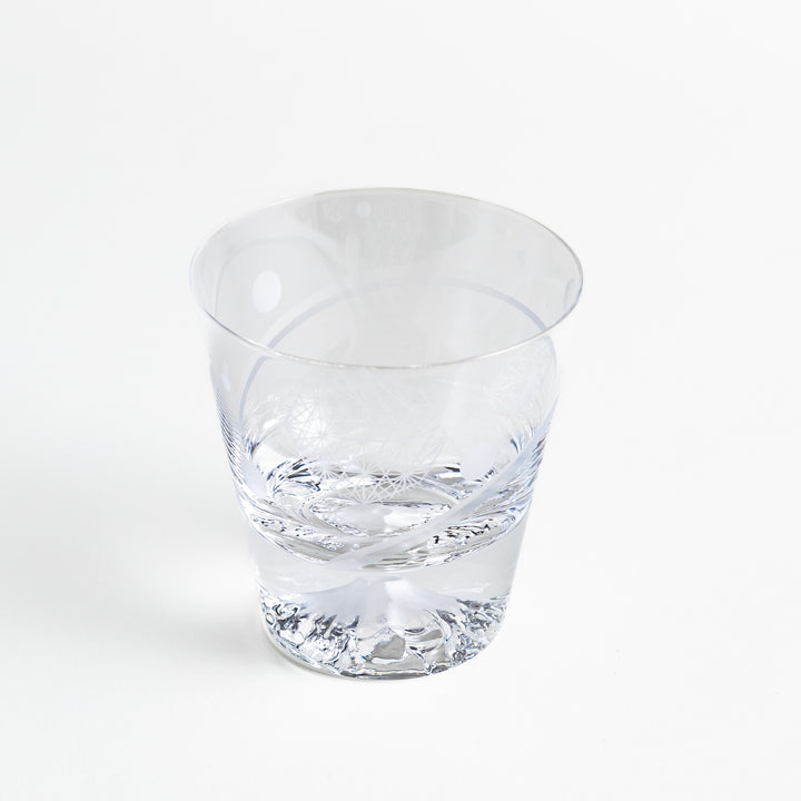 A clear glass with intricate patterns etched in geometric shapes and the bottom showing a mountain design.