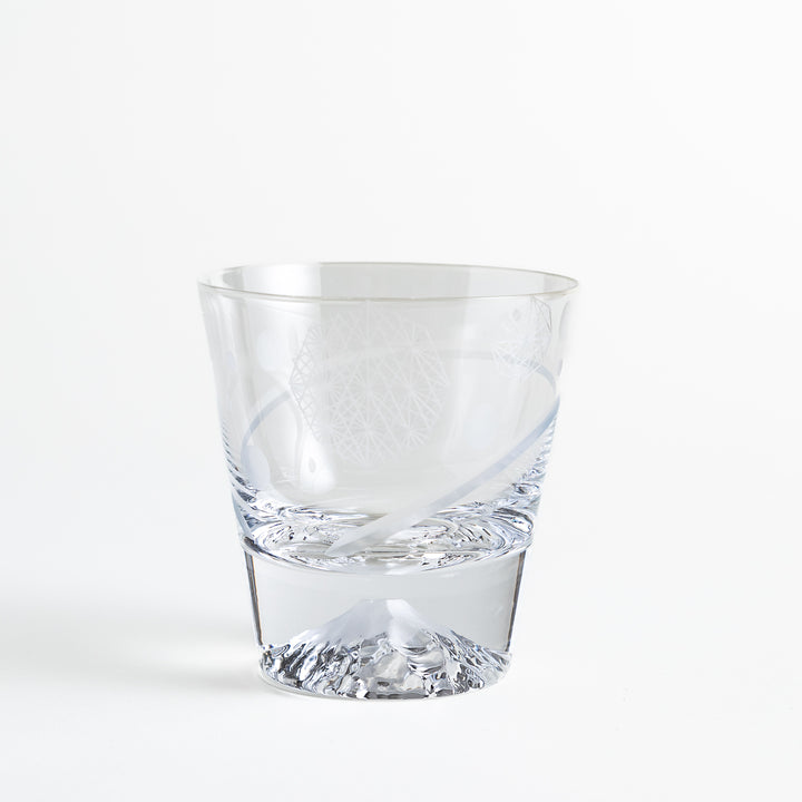 A clear glass with an intricate geometric design, showcasing a low pedestal base and Mount Fuji relief at the bottom, viewed from the side.