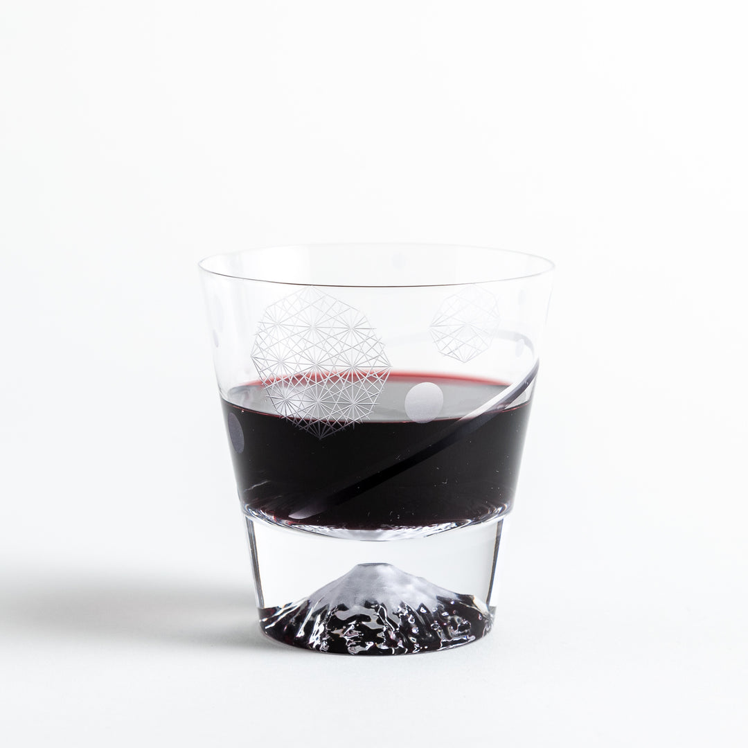 A rocks glass with a geometric pattern and Mount Fuji base, filled with red wine.