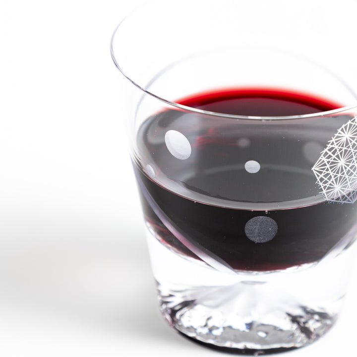 The side of a rocks glass with red wine, showcasing the pattern and Mount Fuji base.