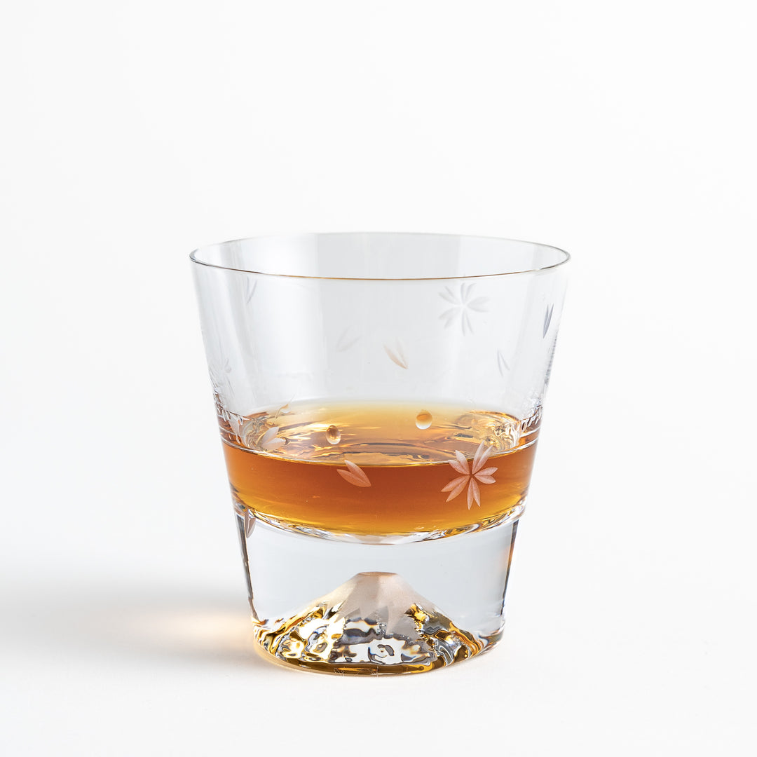 Whisky in a Sakura-themed glass with a mountain base, showing a clear floral pattern etched on the sides of the glass.