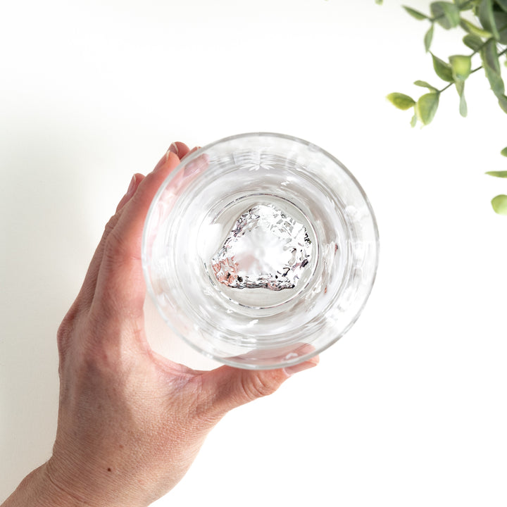 Overhead view of a hand holding a clear glass with a sakura pattern with a mountain design.