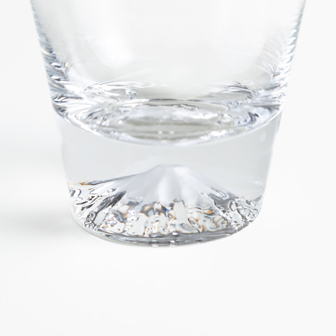 Close-up of a clear glass with a visible mountain-shaped design at the base, showing fine details of the shape and texture.