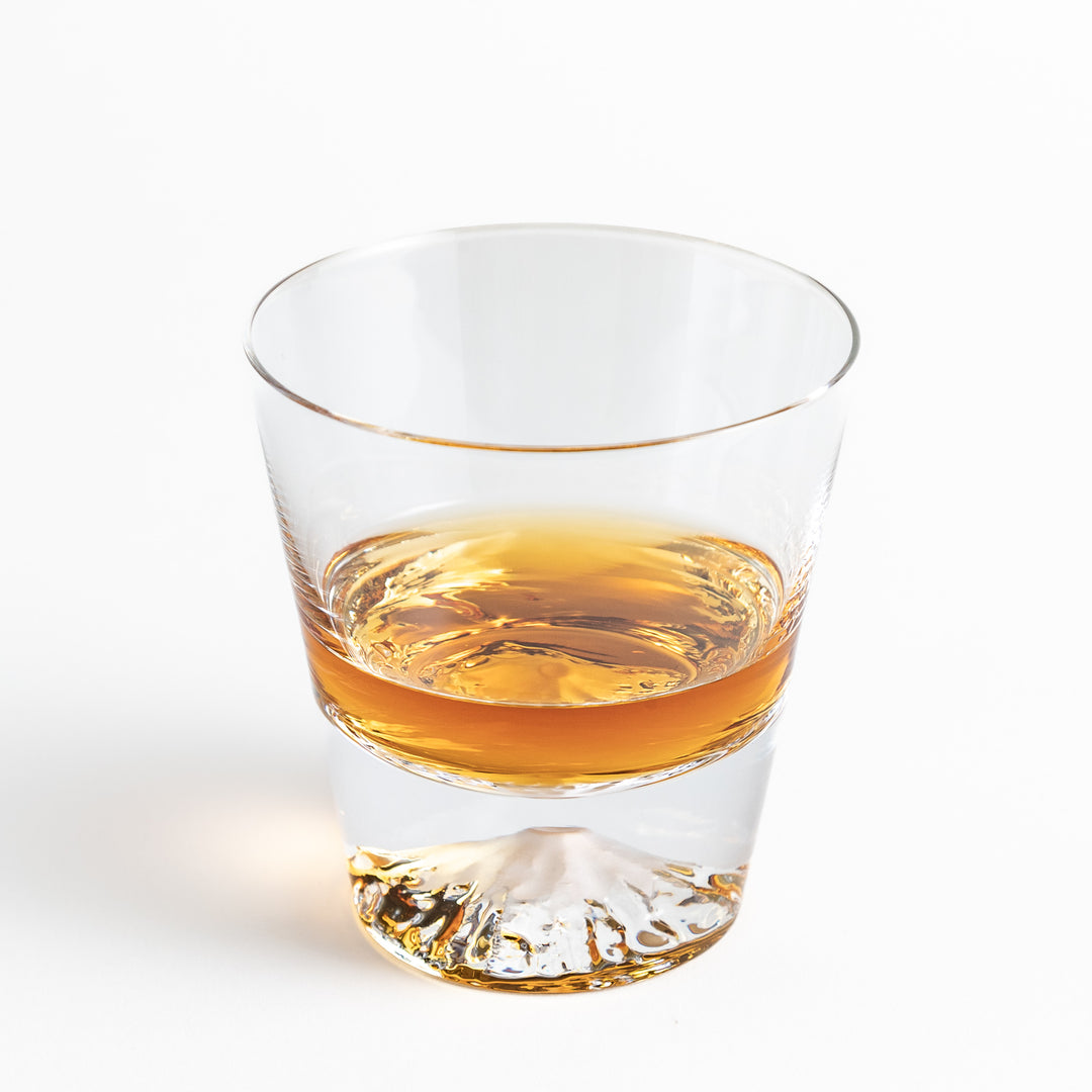 A clear glass filled with Whisky, showing the mountain shape at the base.